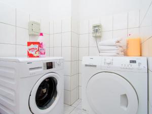 uma máquina de lavar roupa branca numa casa de banho com azulejos brancos em Hostel Bohemia em Praga