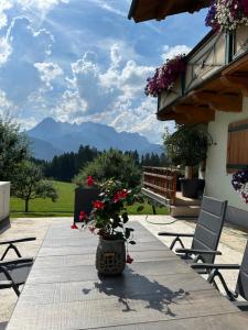 a table with flowers on a patio with mountains in the background at Frische Bergluft und ländlicher Charme - Ihr aktiver Urlaub am Mühlauhof in Mühlbach