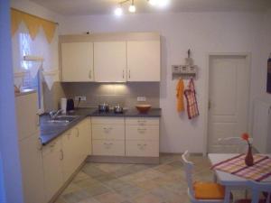 a kitchen with white cabinets and a table and a sink at Landhaus Kopendorf in Bojendorf