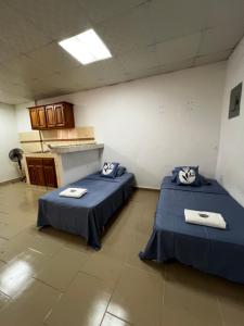 two beds sitting in a room with a kitchen at Apartamentos La Villa in Los Santos