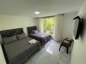 VillamaríaHospedaje Los Termales的一间卧室设有两张床、一个窗口和椅子
