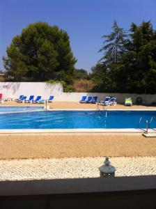 a swimming pool with blue lounge chairs next to it at Apartamento Praia do Vau in Alvor