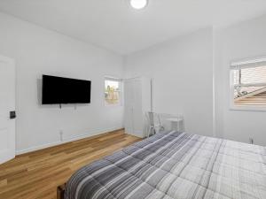 Schenley HeightsにあるBloomfield, Shadyside !A Modern and Bright Private Bedroom with Shared Bathroomの白いベッドルーム(ベッド1台、薄型テレビ付)