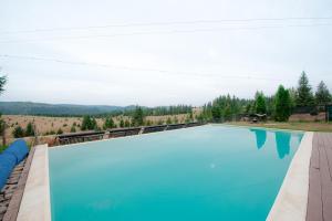 a large swimming pool with a train in the background at Cabana Visul Muntilor Belis in Beliş