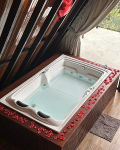 a bath tub with red flowers around it at Chalé Guiados Pelo Alto in São Pedro de Alcântara
