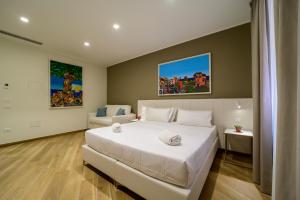 Un dormitorio con una gran cama blanca y un sofá. en B&B Maqueda - Room & Suite, en Palermo
