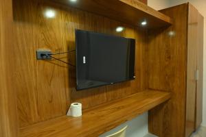 a television on a wooden wall with a roll of toilet paper at Lolita Heights Hotel in Tacloban