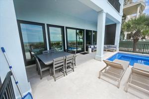 a patio with a table and chairs and a swimming pool at 3 Singleton Beach - Oceanfront Estate, Private Pool, Elevator, FREE Activities Included in Hilton Head Island