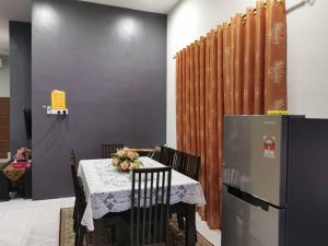 a dining room with a table and a refrigerator at Homestay Sulong in Kuala Rompin
