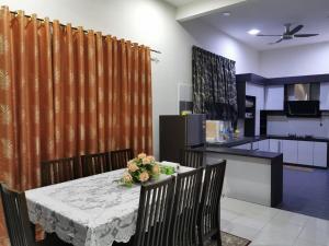 a dining room with a table and a kitchen at Homestay Sulong in Kuala Rompin