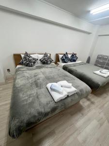 two beds in a bedroom with towels on them at JR Shin-Osaka 30s, Direct to Kansai Airport 關西空港直達,Shinkansen to Tokyo, Tokyo & Nagoya, Universal Studio 16 mins, Umeda 6 mins, Kyoto 25 mins, Early Check-In in Osaka +24 photos