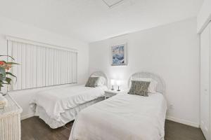 two beds in a room with white walls at Shore Serenity in Bradenton +43 photos