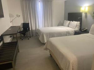 a hotel room with two beds and a desk at Fiesta Inn Nogales in Nogales