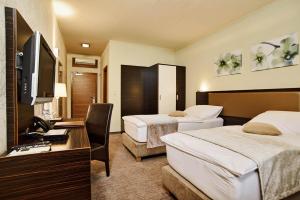 a hotel room with two beds and a television at Privilege - EMPIRE Hotels Group in Košice