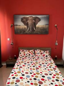ein Schlafzimmer mit einem Elefantengemälde an einer roten Wand in der Unterkunft Résidence Corail in Arafat
