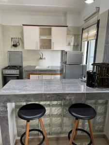 eine Küche mit zwei Barhockern an der Theke in der Unterkunft Résidence Corail in Arafat