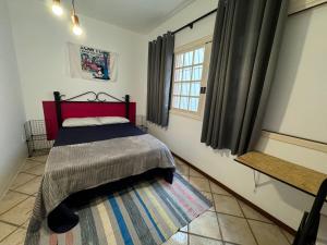a bedroom with a bed with a red headboard and a window at neighbor.HUB hostel & coliving FLORIPA in Florianópolis