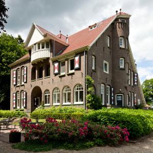 ein großes Backsteingebäude mit rotem Dach in der Unterkunft Villa Rozenhof in Almen