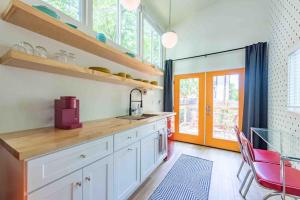une cuisine avec des placards blancs et une chaise rouge dans l'établissement Unique Vintage Vibes - Cozy Tiny Home close to UT, à Austin