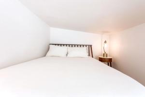 a white bed with two pillows in a room at Cozy and Bright Mid-Century Gem in Eastside Action in Austin