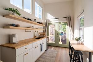 奥斯汀BoHo Tiny Home - Walkable to the Best of East Austin的厨房配有白色橱柜、桌子和柜台