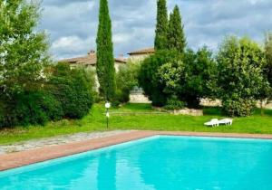 een zwembad in een tuin met bomen en een huis bij Chianti House in Gaiole in Chianti