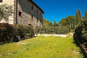een stenen gebouw met een grasveld naast een gebouw bij Chianti House in Gaiole in Chianti