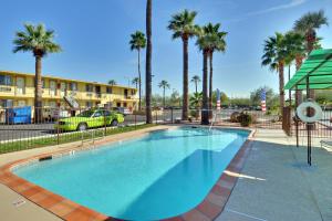 een groot zwembad met palmbomen en een gebouw bij American Executive Inn Mesa in Mesa