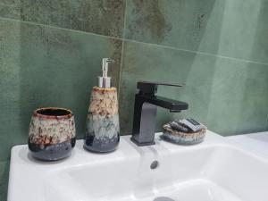 ein Waschbecken mit einem Wasserhahn und zwei Tassen in der Unterkunft Домът на Билкарката in Plowdiw + 78 Fotos