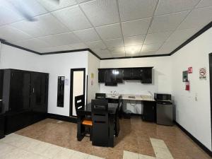 a kitchen with black cabinets and a table in a room at Hotel Garcias Suites, Linares in Linares