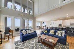 a living room with blue couches and a kitchen at 6 Collier Beach Road- Oceanfront, Large Pool, Elevator, FREE Activities Included in Hilton Head Island