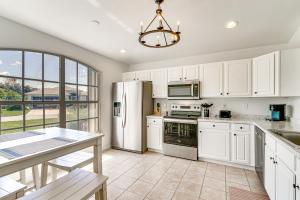a kitchen with white cabinets and appliances and a table at 4 Mi to Beach Beach Haven with Water Views! in Fort Myers