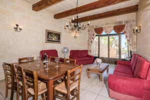sala de estar con mesa de madera y sillas rojas en 4 Bedroom Farmhouse with Private Pool & Views, en Nadur