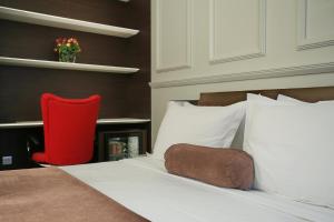 a bedroom with a bed with a red chair at Belgreat Premium Suites in Belgrade