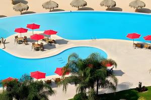 an aerial view of a resort pool with tables and red umbrellas at Exquisite Oceanfront Condo outstanding experience! in Puerto Vallarta