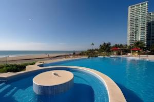 a large swimming pool next to a beach at Exquisite Oceanfront Condo outstanding experience! in Puerto Vallarta