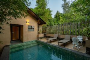 a swimming pool with two chairs and a house at Tea Terrain Resorts & Spa in Vagamon