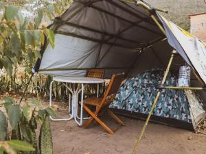 a tent with a table and a chair in it at Camping Filhos da Floresta - Vale do Capão in Vale do Capao