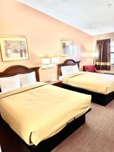 una habitación de hotel con dos camas y una silla en Owensville Inn, en Owensville