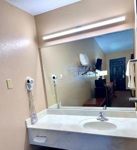 Un baño con lavabo y un espejo grande. en Owensville Inn, en Owensville