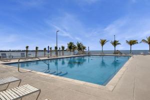 a large swimming pool with palm trees and the ocean at Green Turtle Retreat at Ocean Isles in Marathon