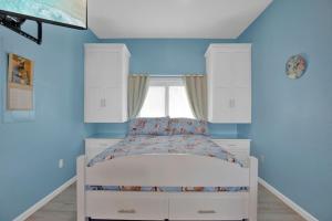 a bedroom with blue walls and a bed with a window at Ocean Isles Mackeral Row in Marathon +19 photos