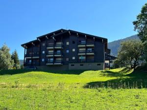ein Gebäude auf einem Hügel mit einem grünen Feld in der Unterkunft Studio vue montagne à 200m des pistes in Arâches-la-Frasse