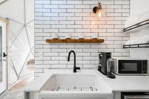 a white kitchen with a sink and a microwave at Tranquil Dome at Faraway Camp in Luray