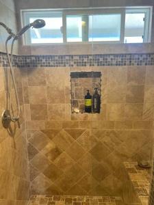 a bathroom with a shower with two bottles in it at SurfCity Villa Chateau Relaxeau in Huntington Beach