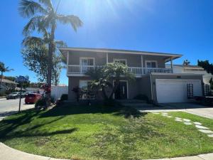a house with a palm tree in front of it at SurfCity Villa Chateau Relaxeau in Huntington Beach