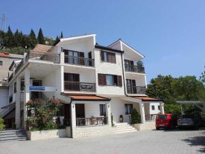 a white building with balconies and cars parked in a parking lot at Guest House San Antonio-Comfort One Bedroom Apartment with Balcony no 1 in Ploče