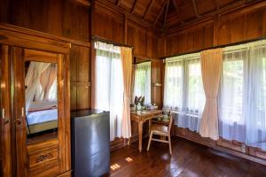 a bedroom with a bed and a desk and windows at The Dukuh Retreat in Tabanan