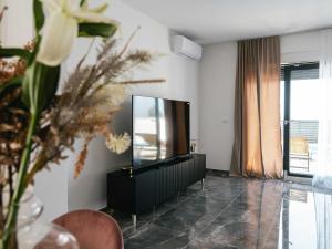 un soggiorno con TV e vaso di fiori di Villa La Ze - Three Bedroom Villa with Swimming Pool a Rogoznica (Rogosnizza)