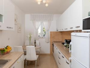 a kitchen with white cabinets and a table with chairs at 2 room apartment with hot tub in Mlini